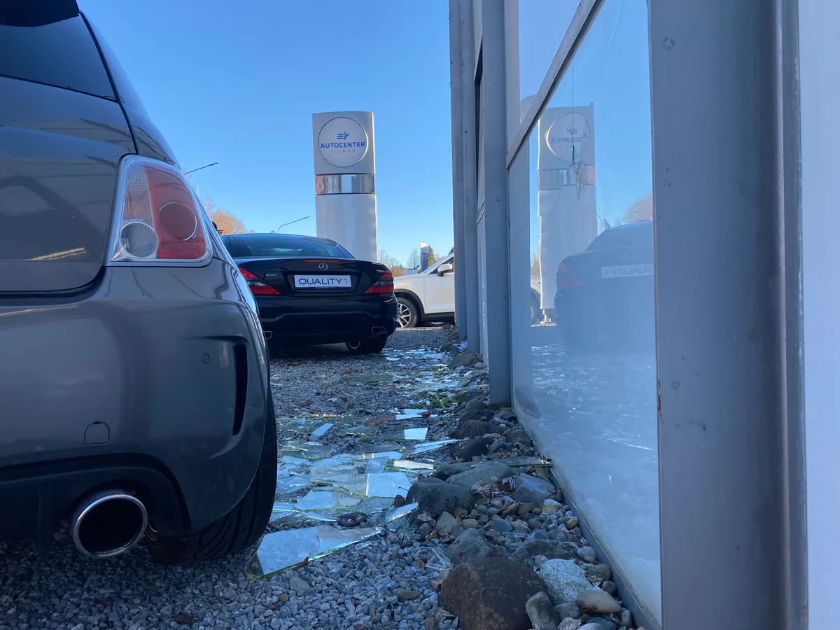 Zerborstene Fensterscheiben nach der heftigen Detonation in Illnau. Man sieht zwei Autos vor dem Auto Center Illnau im Industriegebiet und Scherben am Boden.